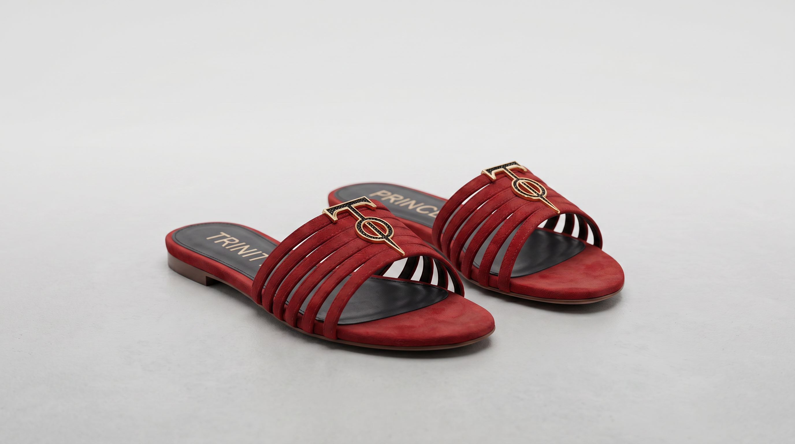 Red sandals with gold accents on a light gray background
