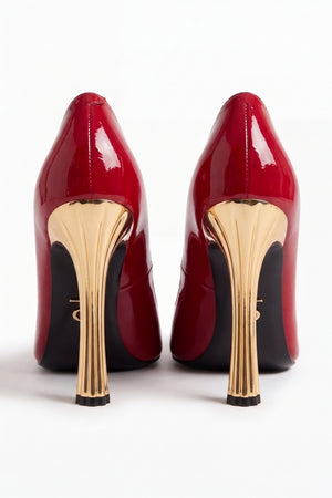 Pair of red high-heeled shoes with gold soles on a white background