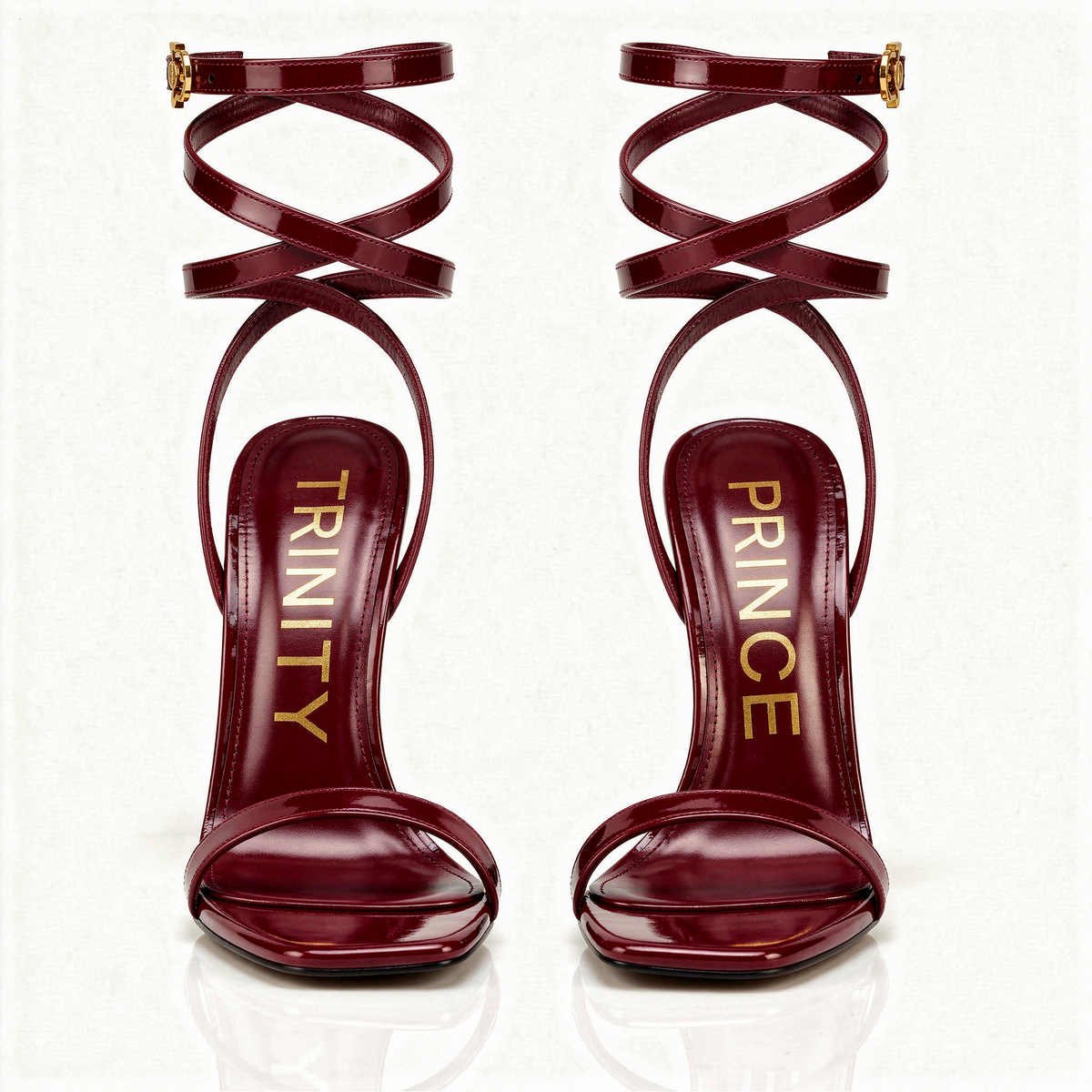 Pair of red high-heeled sandals with 'Trinity' and 'Prince' branding on a white background